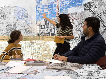 students and a professor looking over architecure planning designs