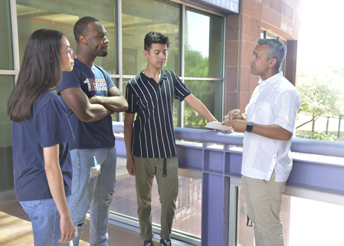 four people including students and professors standing outside discussing urban planning