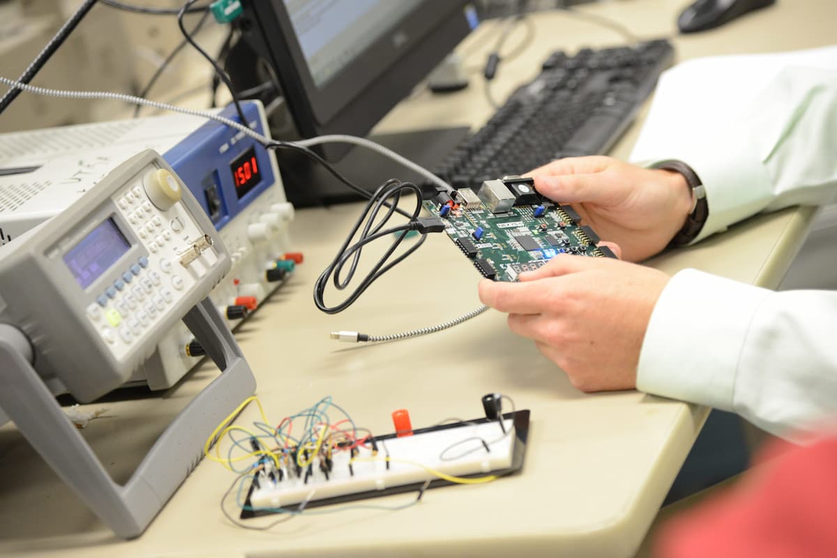 student holding a circuit board in a lab coat
