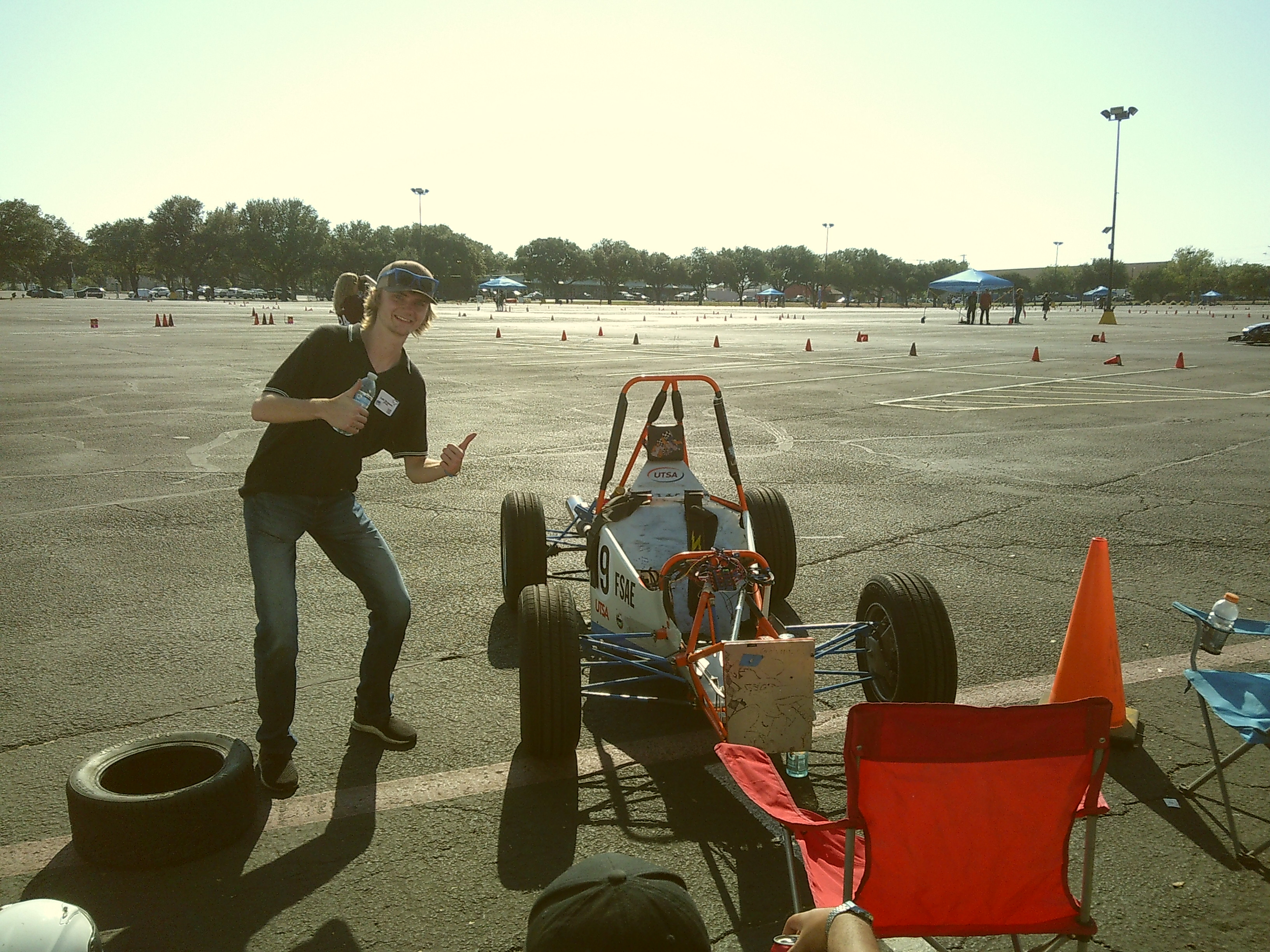 Student posing with their car