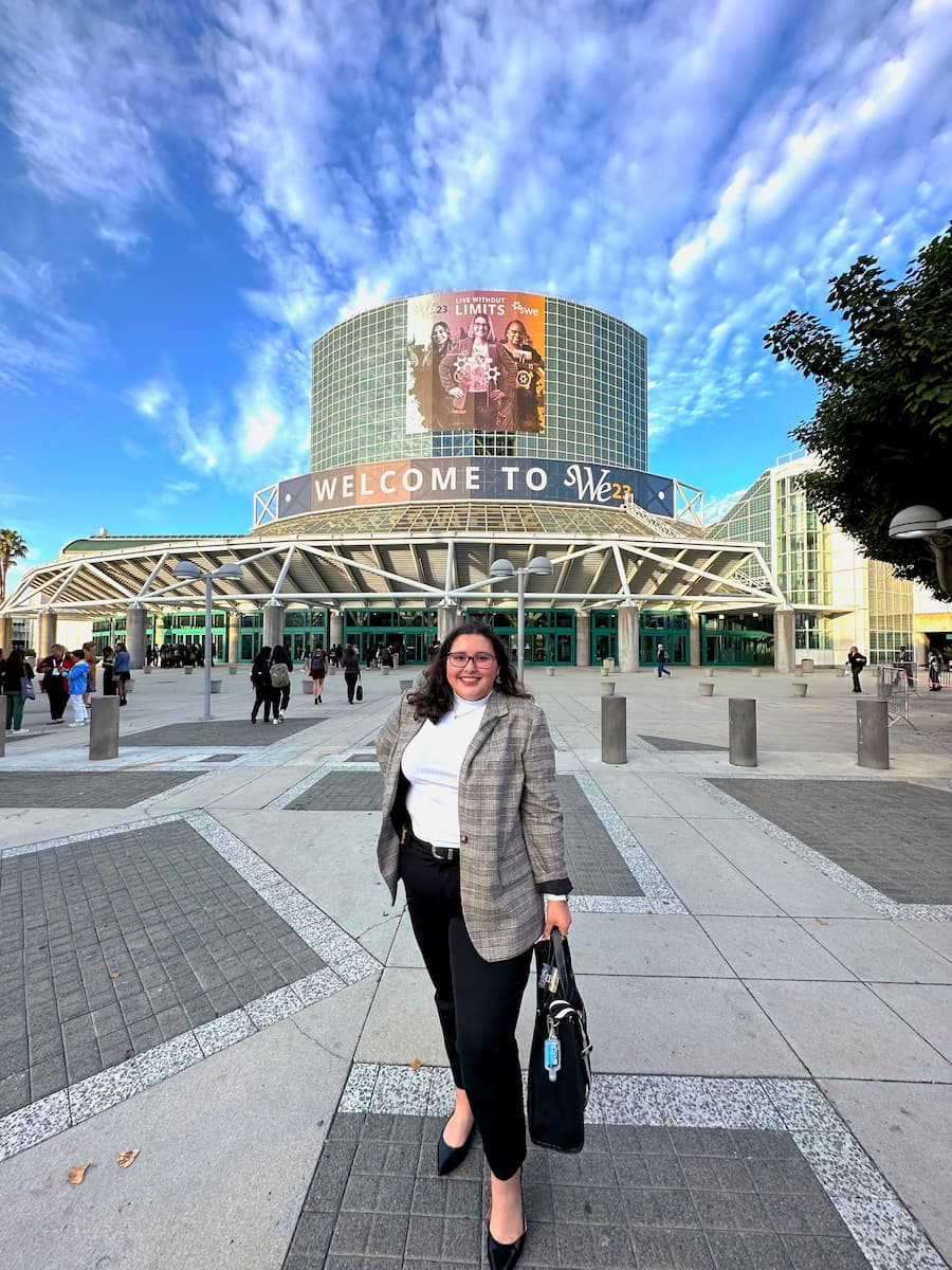 Sydney Weiss standing confidently in front of the WE23 conference venue in business attire.