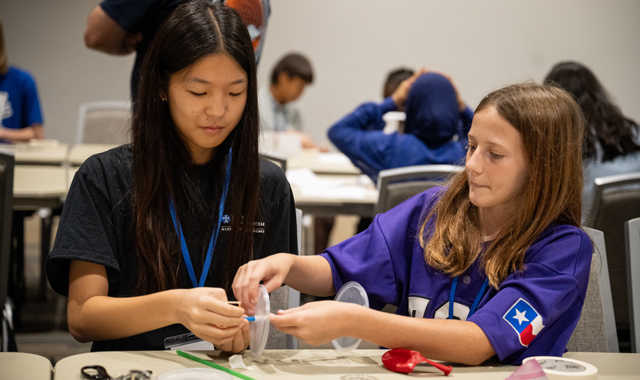 Two students collaborating on an engineering project during a PREP program activity, surrounded by peers working in the background