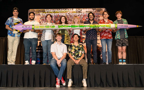 Students holding a rocket at competition