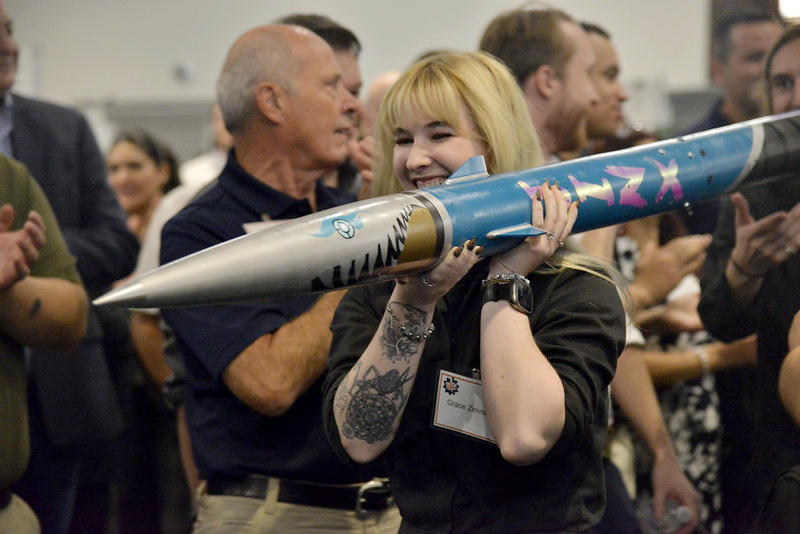 Student celebrates while holding a large model rocket at the Fall 2025 Tech Symposium